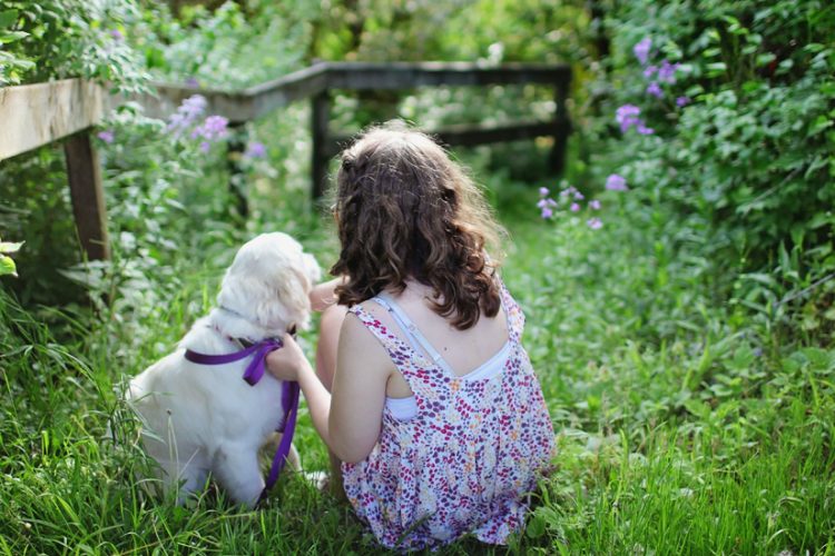 Girl Sitting with Dog in Field