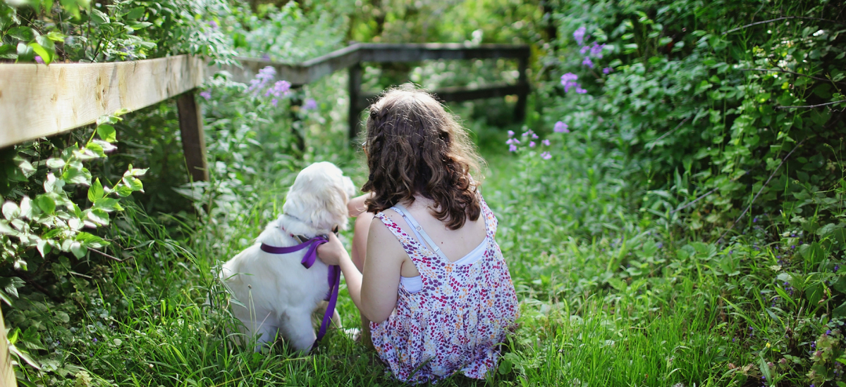 Girl Sitting with Dog in Field