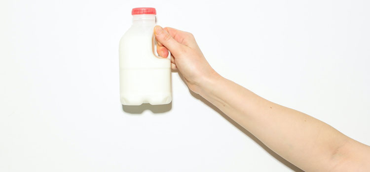 Outreached arm holding a small container of milk