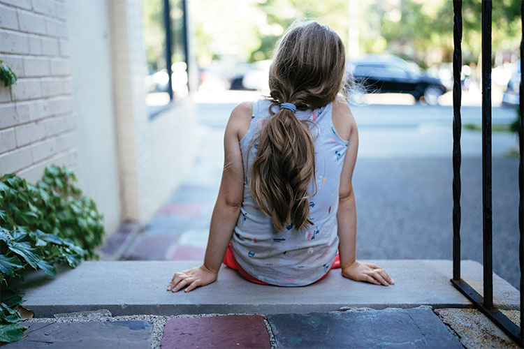 Child sitting on steps with facing away from camera