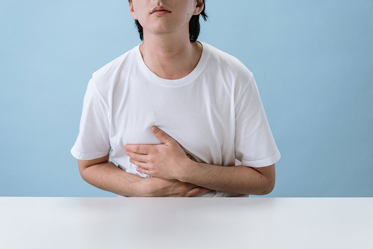 Young person at a table clutching their stomach