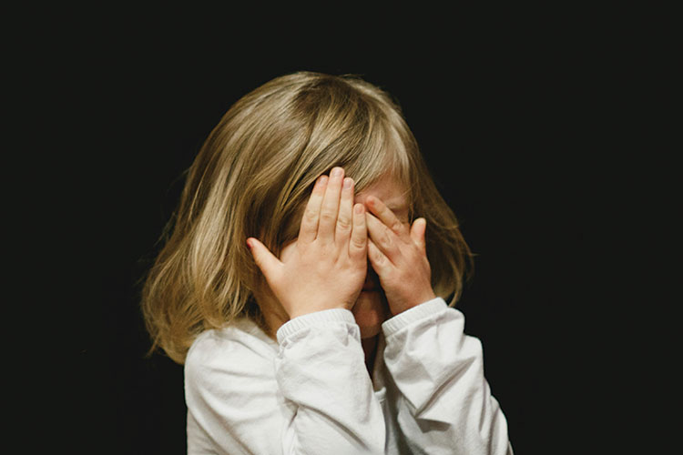 Young Child with Blonde Hair Covering Their Eyes