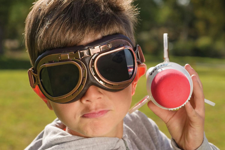 Child wearing googles with a toy rocket in their hand