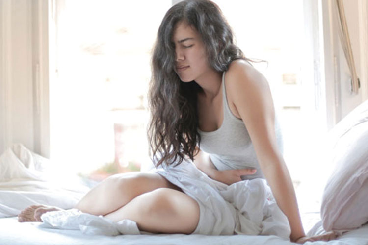 girl in pain sitting up in a bed